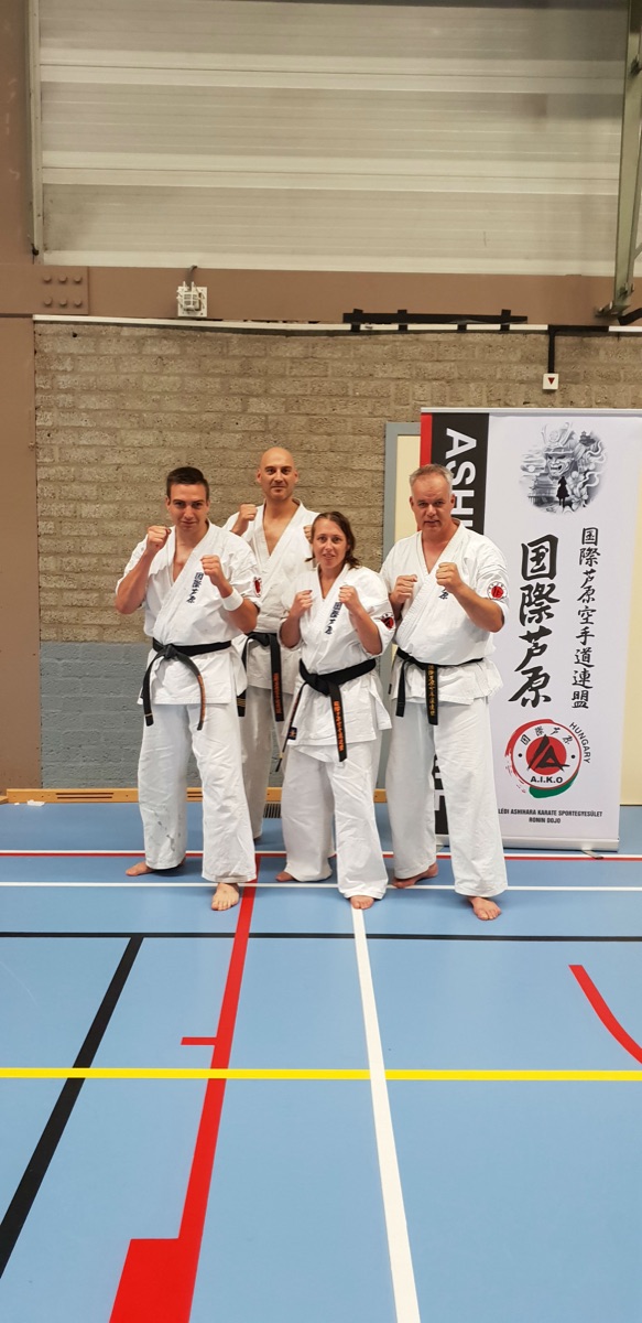 Vier trainers van Team Doragon met zwarte band voor de Ashihara-banner